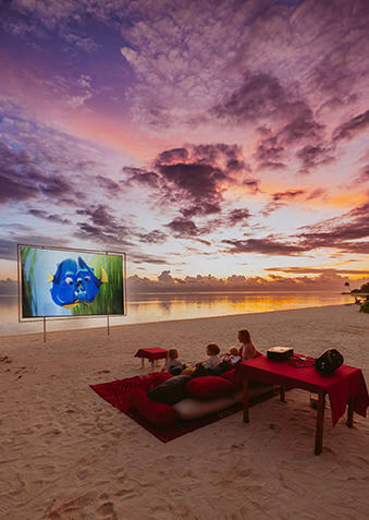 Семейный киносеанс на фоне заката над океаном